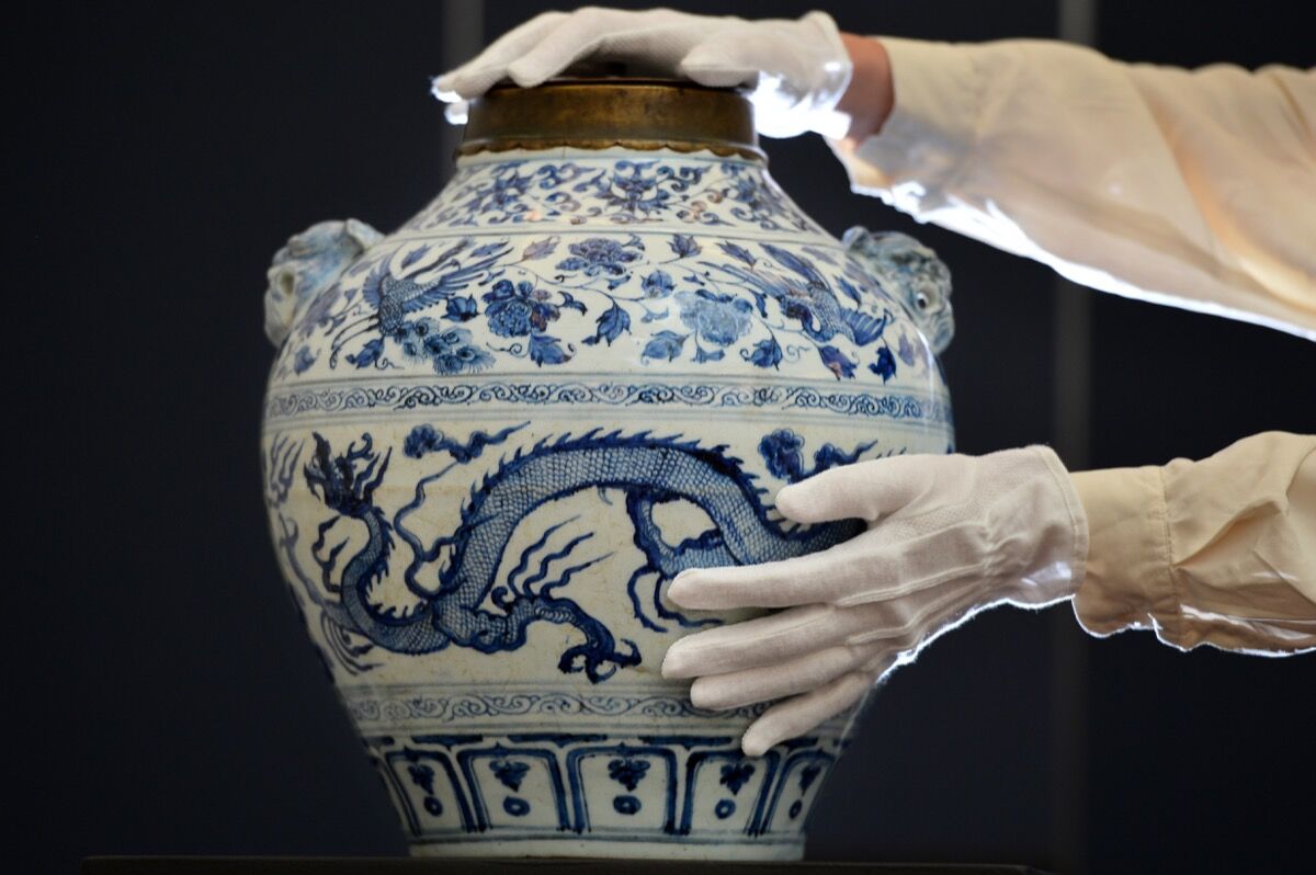 An Sotheby&#x27;s employee poses with a Yuan dynasty blue and white &#x27;Dragon and Phoenix&#x27; jar sold in Sotheby&#x27;s Fine Chinese Ceramics and Works of Art auction in London on November 2, 2012. Photo by BEN STANSALL/AFP/Getty Images.