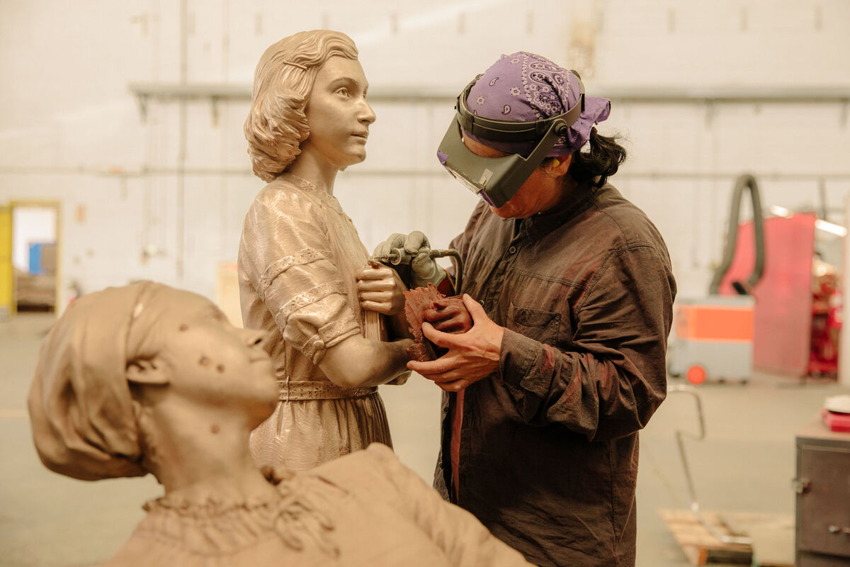 Metal finisher Insun Kim is refining details on a sculpture of Anne Frank for Studio EIS. Photo by Ricky Rhodes for Artsy. 