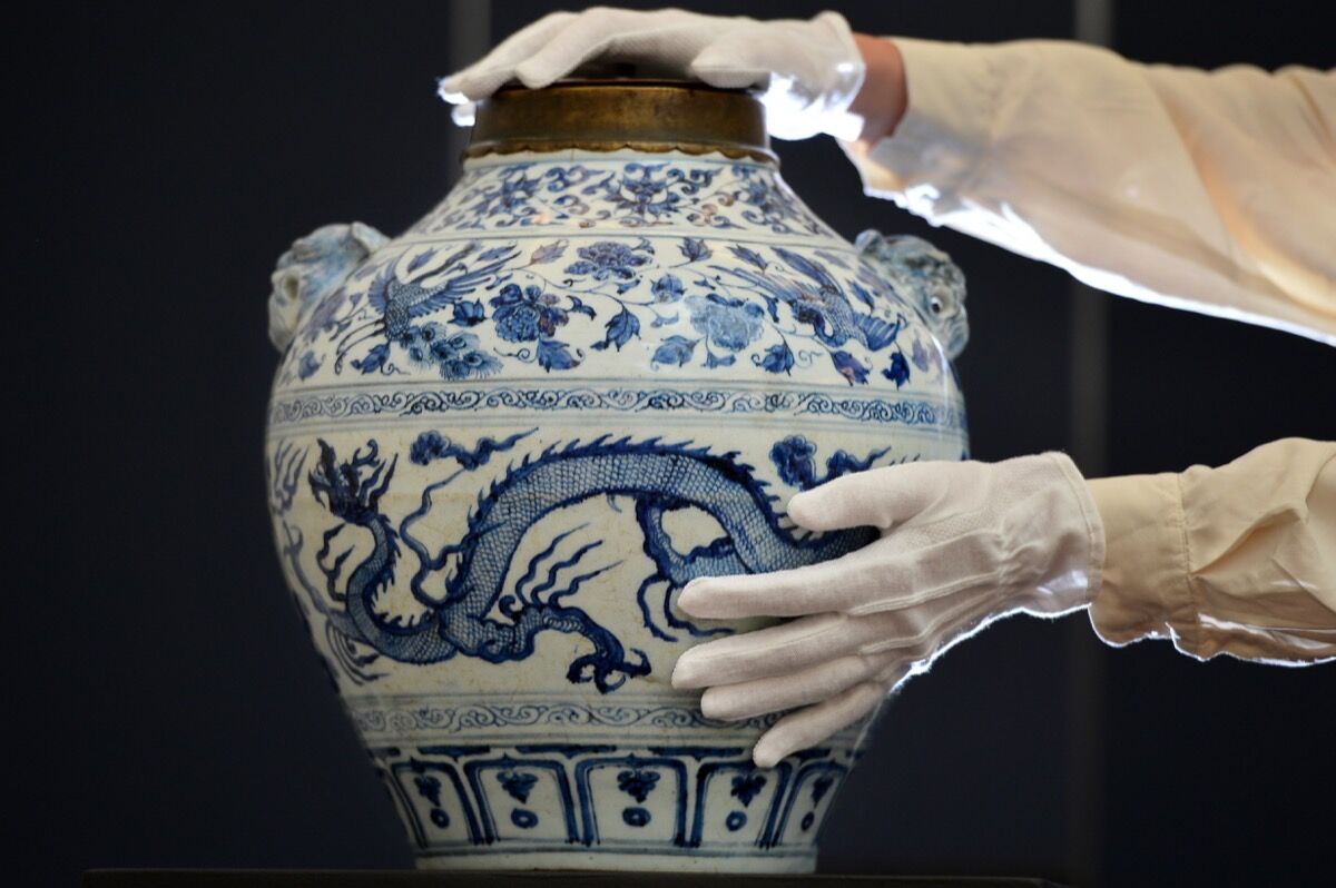 An Sotheby's employee poses with a Yuan dynasty blue and white 'Dragon and Phoenix' jar sold in Sotheby's Fine Chinese Ceramics and Works of Art auction in London on November 2, 2012.  Photo by BEN STANSALL/AFP/Getty Images.