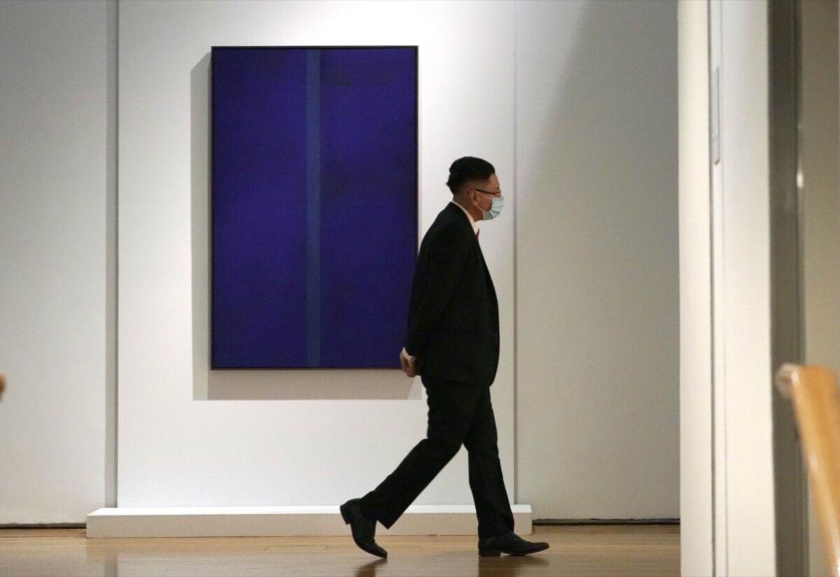 Un guardia pasa junto al Onement V de Barnett Newman mientras Christie's presenta ONE, una subasta de arte global del siglo XX que abarca cuatro ciudades en un formato de estilo de relevos. Foto de Timothy A. Clary / AFP. Imagen a través de Getty Images.