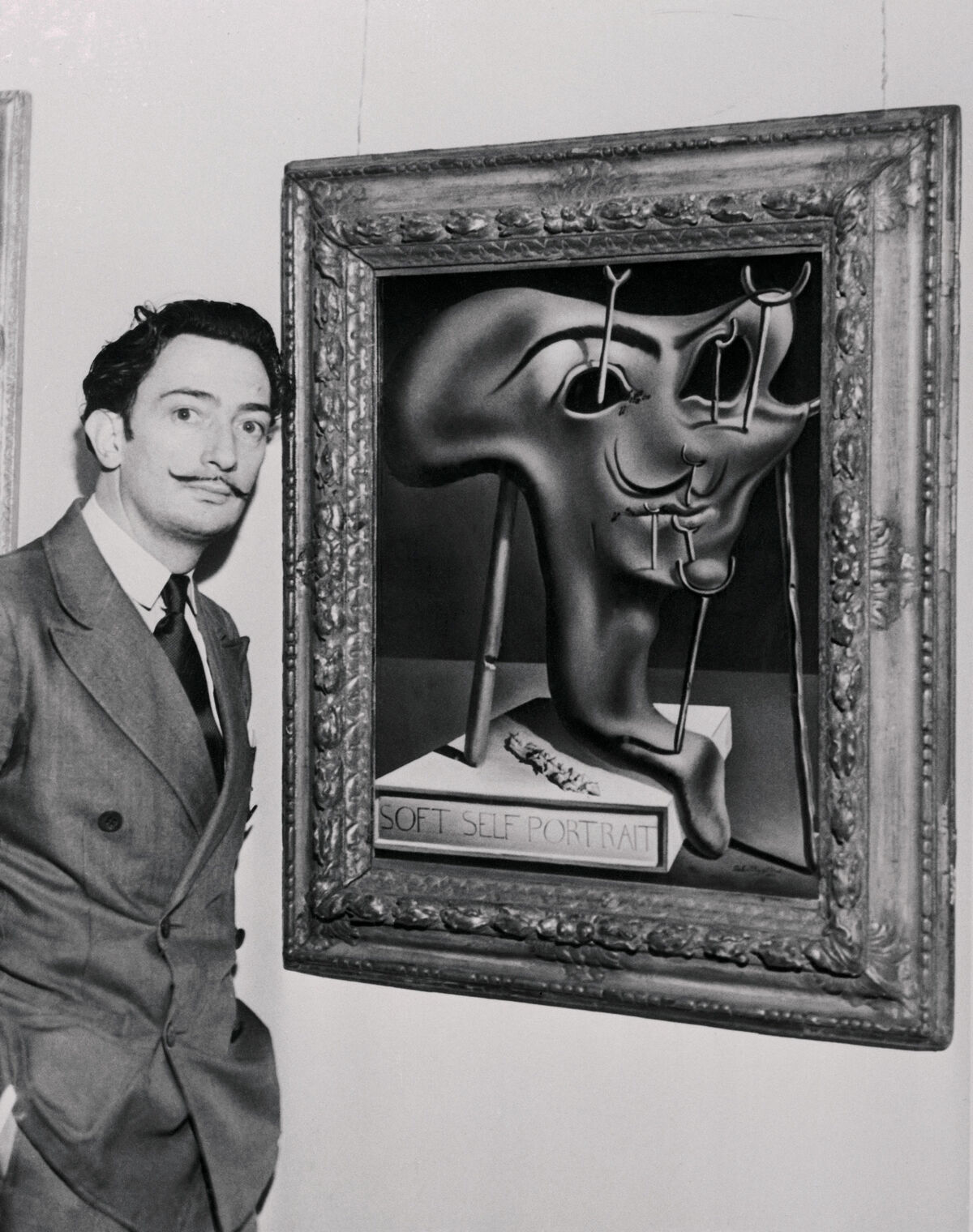 Salvador Dali with his artwork Soft Self-Portrait at the Julien Levy Gallery, 1941. Photo by Bettmann / Contributor via Getty Images.