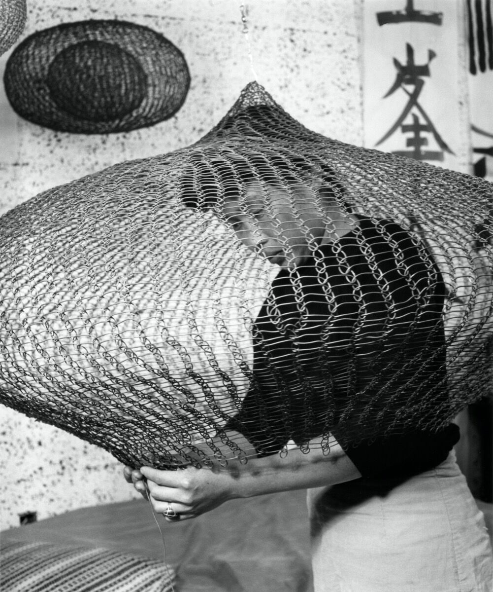Portrait of Ruth Asawa working inside the lobe of a looped-wire sculpture, 1957. Photo by Imogen Cunningham. © 2019 Imogen Cunningham Trust. Courtesy of Imogen Cunningham Trust.