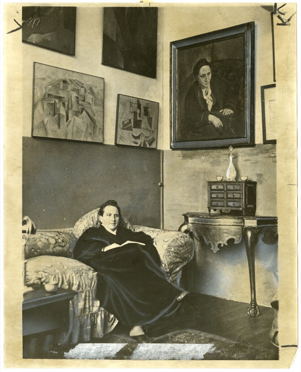 Gertrude Stein sitting on a sofa in her Paris studio, 1930. Image by World Wide Photos, via Wikimedia Commons.