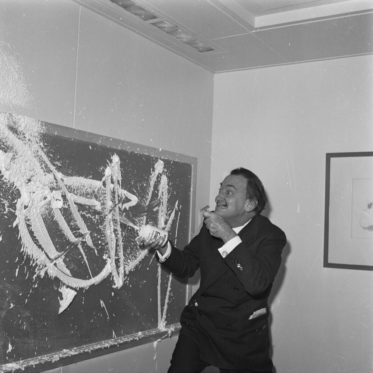 Salvador Dali paints with shaving cream on the blackboard of the children’s playroom on the S.S. United States. Image via Getty Images.