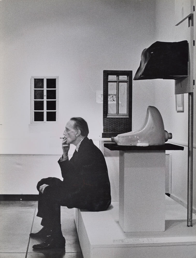 Duchamp smoking in front of Fountain, Duchamp Retrospective, Pasadena Art Museum