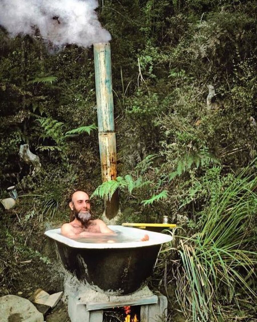 Austrian artist Friedensreich Hundertwasser in his makeshift tub in the New Zealand rainforest.