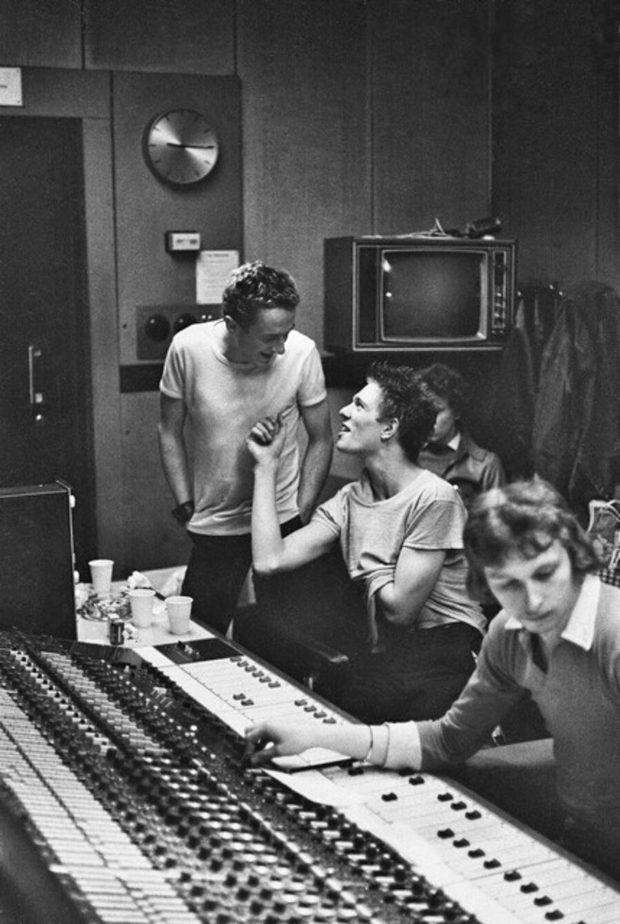 The Clash. In the recording studio: Mickey Foote engineer and The Clash ‘s live sound man at the mixing desk as Joe Strummer confers with Paul Simonon. CBS Studio 3, Whitfield Street, London. February.