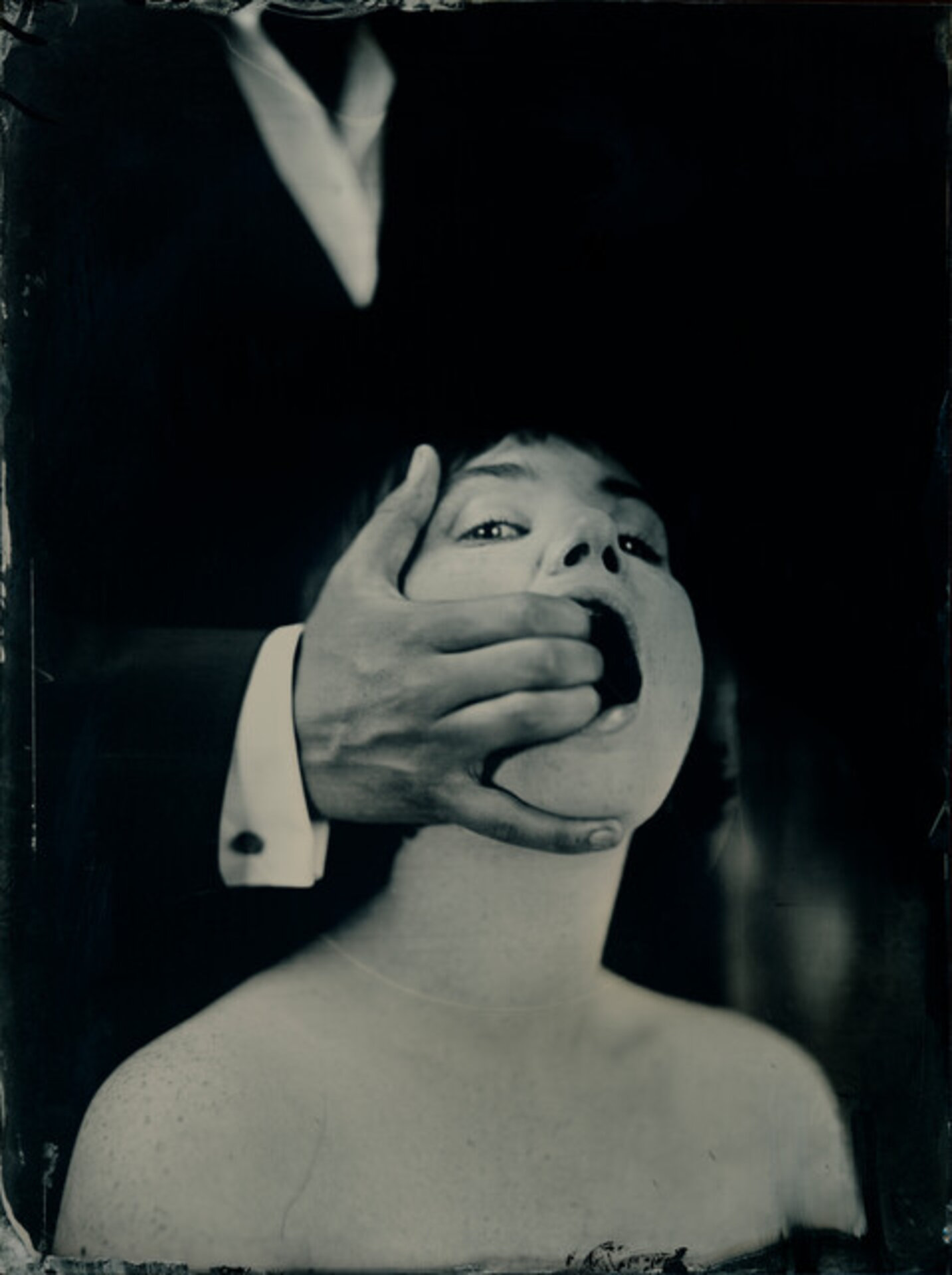 Woman with man’s hand inside mouth