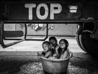 Xyza Cruz Bacani, ‘Jennelyn Bargo's daughter, niece, and nephew take a bath under one of the trucks they use as a temporary home in Smokey Mountain’, 2020