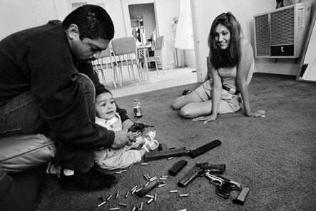 Joseph Rodriguez, ‘The morning after a rival gang tried to shoot Chivo for the fourth time. Chivo teaches his daughter how to hold a .32-caliber pistol. Her mother looks on, Boyle Heights, Los Angeles, CA’, 1993