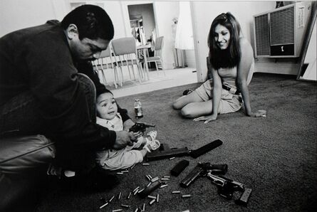 Joseph Rodriguez, ‘The morning after a rival gang tried to shoot Chivo for the fourth time, Chivo teaches his daughter how to hold a .32-caliber pistol. Her mother looks on.’, 1993