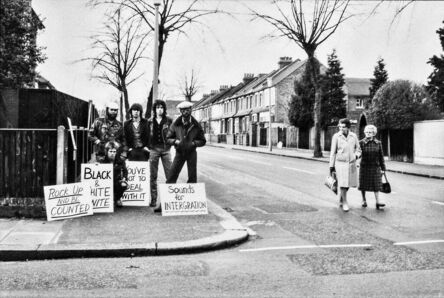 Caroline Coon, ‘Mick Jones (The Clash) and Mykaell Riley (Steel Pulse) demonstrate outside leader of the neo-fascist National Front leader’s head-quarters on Connaught Road, Teddington. Passing local residents look on.’, 1978