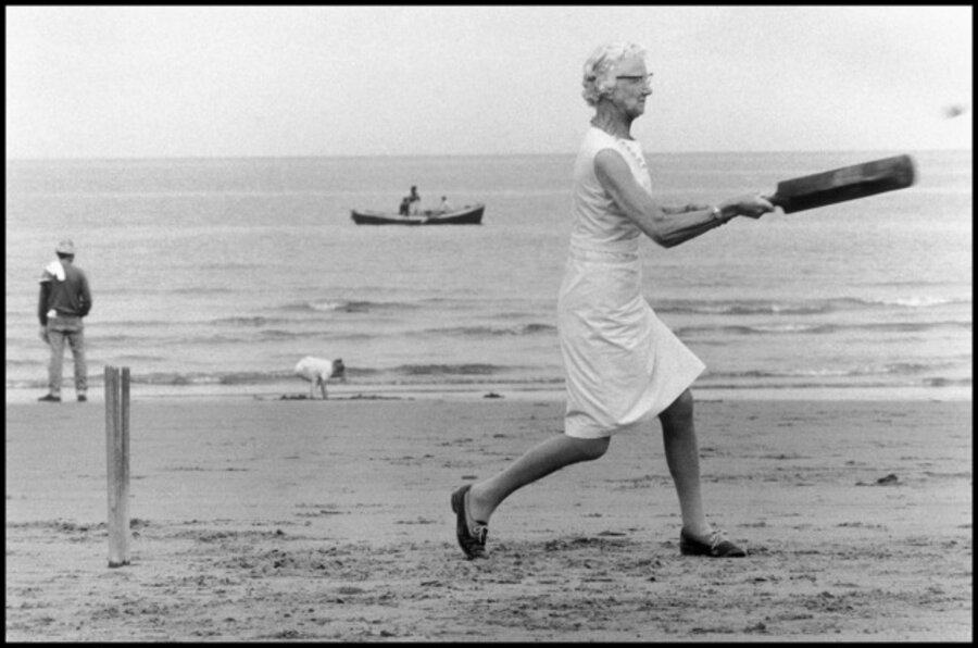 Elderly English woman playing cricket with her family on the beach. Whitby, Yorkshire, Great Britain