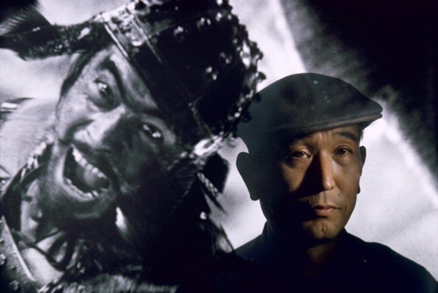 Film director Akira Kurosawa standing before an image of his principal star, Toshiro Mifune, Tokyo, Japan