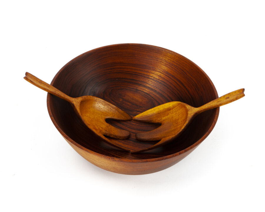 A teak salad bowl with two tongs
