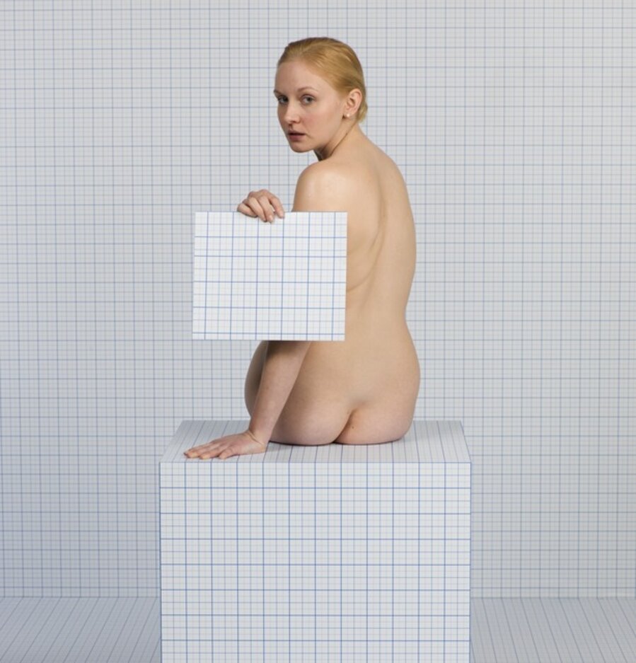 Naked Girl Sitting Down, Turning Towards Camera