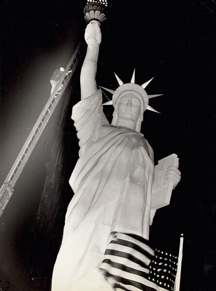Weegee, ‘Man climbs 85-foot ladder to secure torch on the plastic Statue of Liberty erected at Times Square for the Sixth War Loan Drive, New York, November 30’, 1944