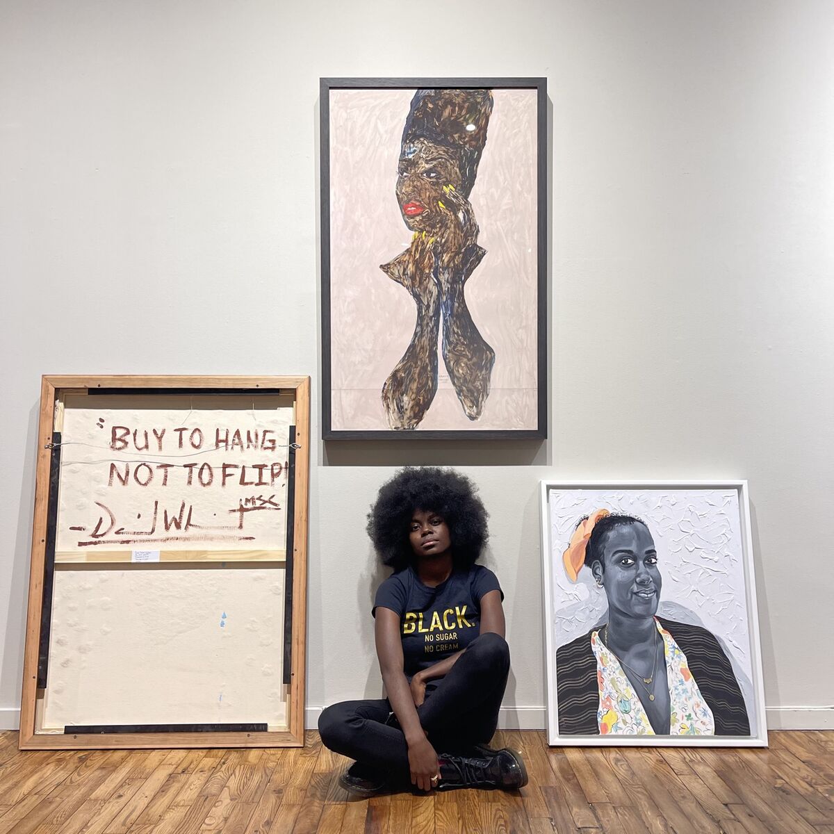 Portrait of Destinee Ross-Sutton with, from left to right, works by David “Mr. StarCity” White (showing the back of the work), Amoako Boafo, and Otis Kwame Kye Quaicoe, from the exhibition “Black Voices: Friend of My Mind.” Courtesy of Destinee Ross-Sutton.