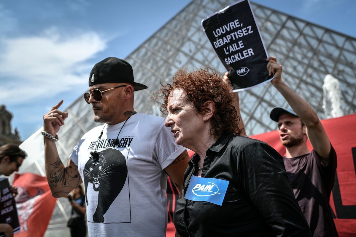 Nan Goldin, artist and founder of PAIN, with the mission head of AIDES, Fred Bladou, during an anti-Sackler protest at the Louvre. Photo by Stephane de Sakutin/AFP/Getty Images.