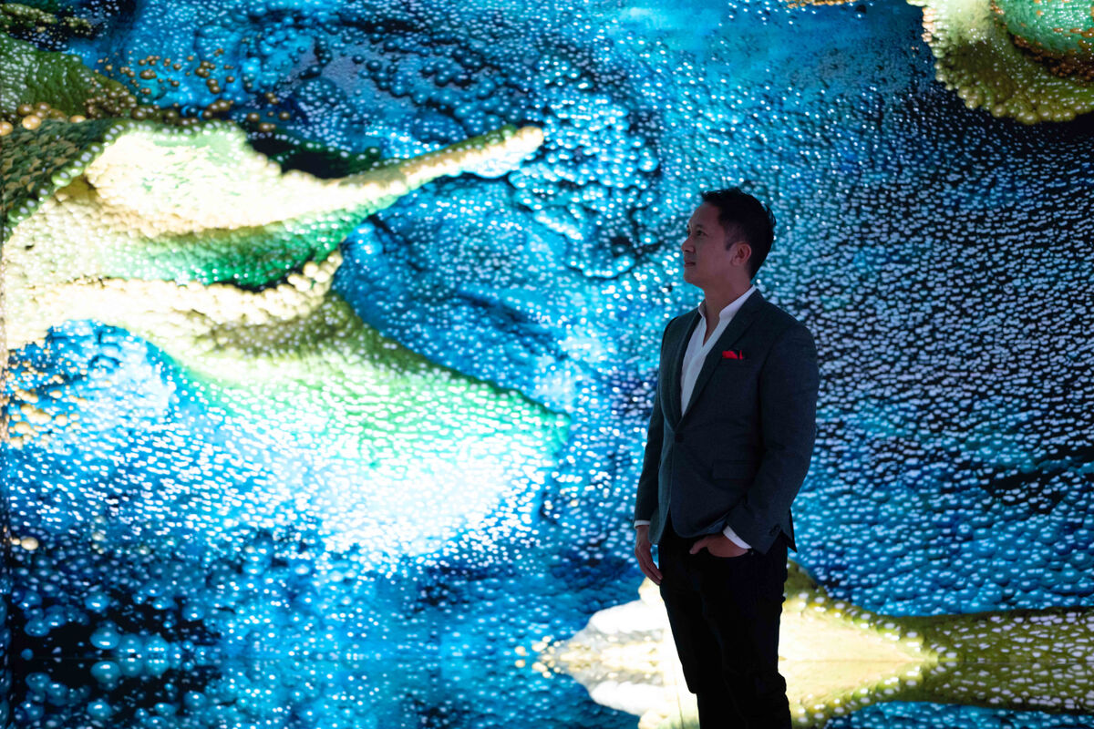 Collector Jehan Chu in front of Machine Hallucinations - Space: Metaverse by Refik Anadol in partnership with Sotheby's at Digital Art Fair Asia 2021 in Hong Kong. Courtesy of Digital Art Fair Asia.