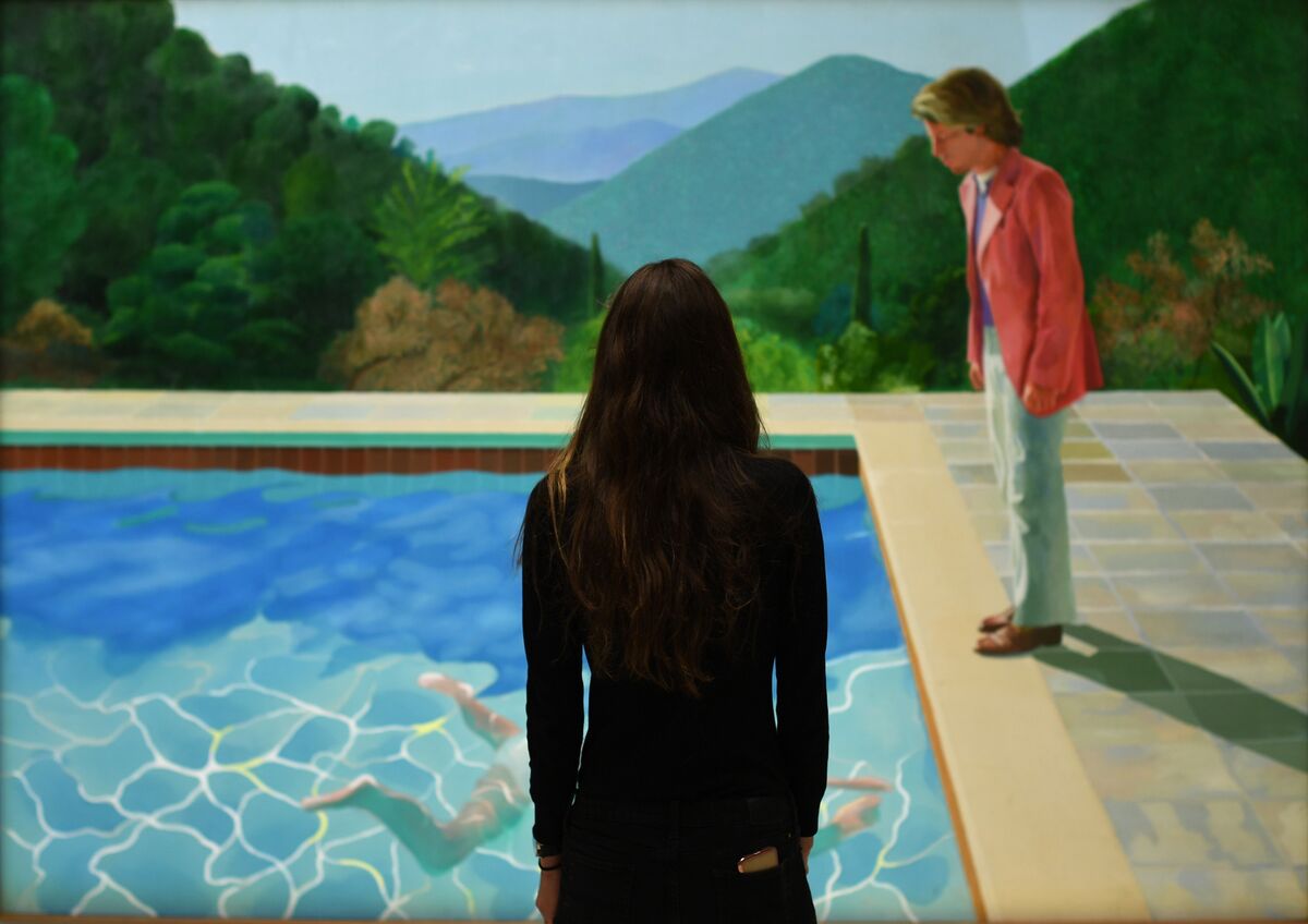 A woman views David Hockney, Portrait of an Artist (Pool with Two Figures), at Christie’s, New York, 2018. Photo by Timothy A. Clary/Getty Images.