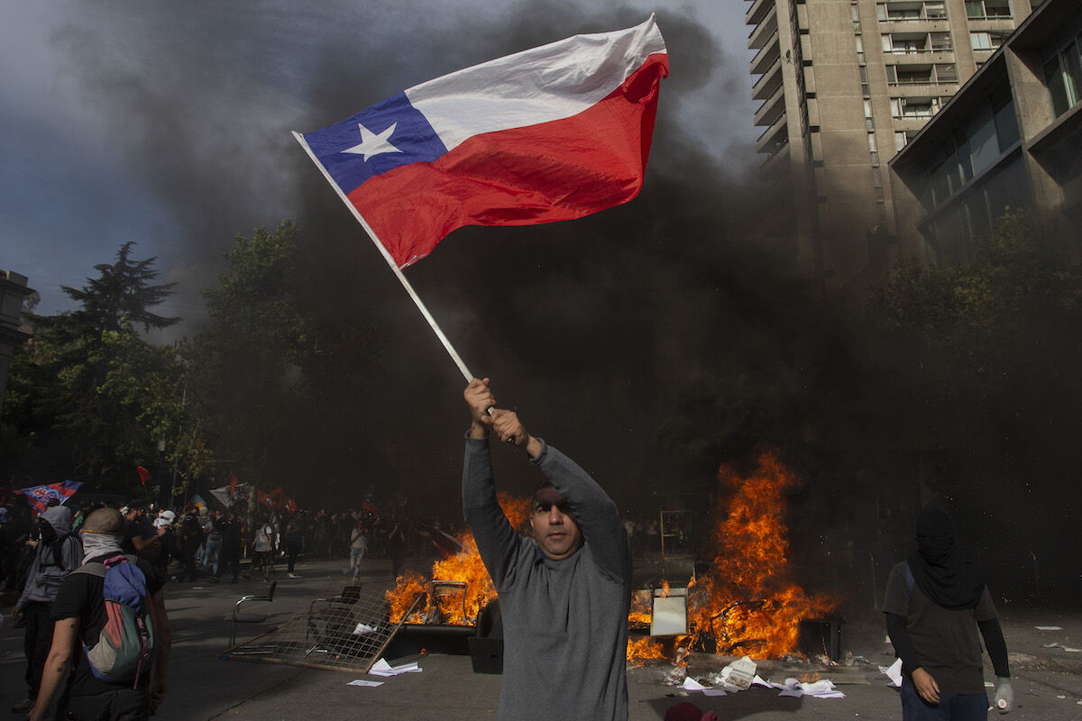 A demonstrator waves a Chilean flag during a protest against the government’s economic policies in Santiago on October 29, 2019. Photo by Claudio Reyes/AFP via Getty Images.
