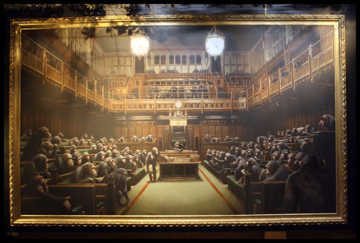 A painting by Banksy formerly titled Question Time, now Devolved Parliament, as it appeared in a 2009 exhibition at the Bristol Museum. Photo by Josh Blair, via Flickr.