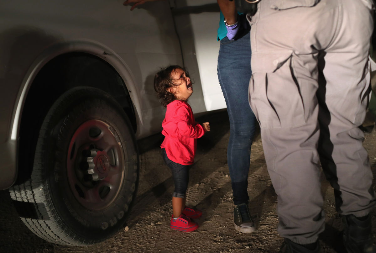 A two-year-old Honduran asylum seeker cries as her mother is searched and detained near the U.S.-Mexico border on June 12, 2018 in McAllen, Texas. Photo by John Moore/Getty Images.