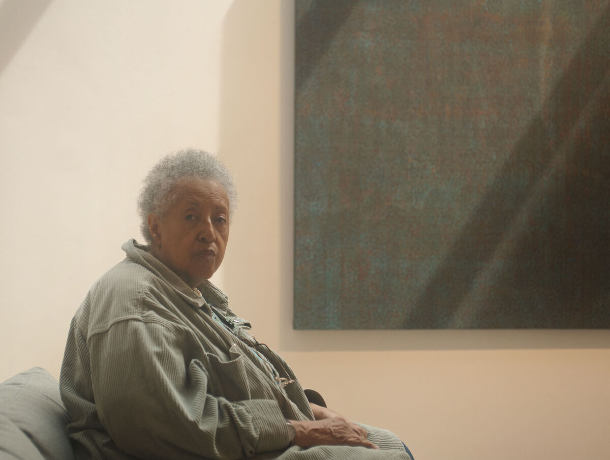 Howardena Pindell with her work at Garth Greenan Gallery by Alex John Beck for Artsy.