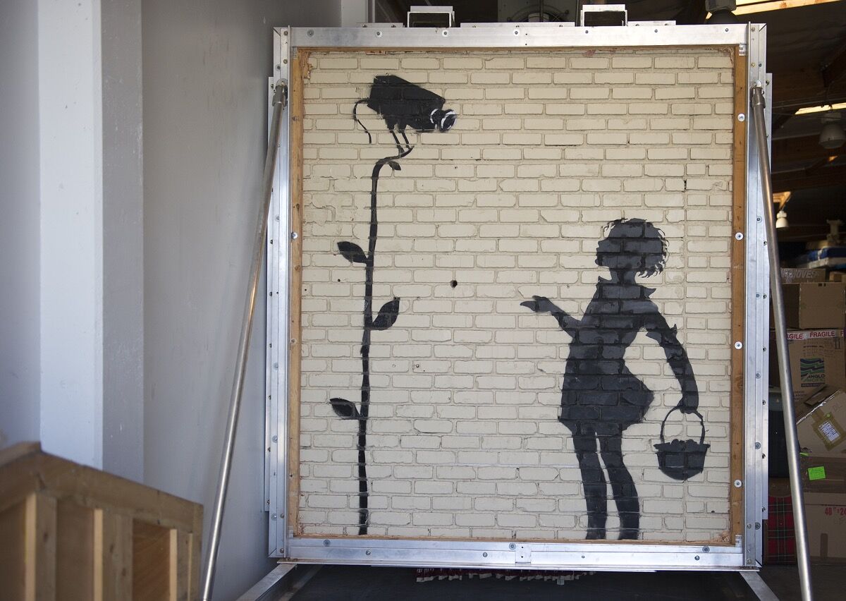 A work by Banksy titled Flower Girl is seen at Julien&#x27;s warehouse in Los Angeles, California August 21, 2013. Photo by Robyn Beck/AFP/Getty Images. 