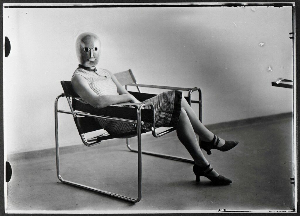 Scène du Bauhaus : Inconnue au masque dans un fauteuil tubulaire de Marcel Breuer portant un masque de Oskar Schlemmer